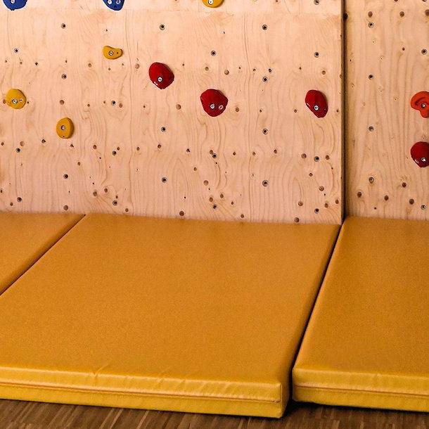 Fallschutzmatte für Kletterwand im Kindergarten. Reduzierte Verletzungsgefahr bei Stürzen.